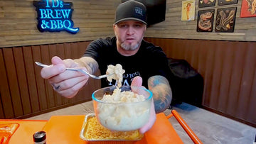 TD holding a bowl of smoked mac and cheese with fire roasted hatch green chiles and a crushed pork rind topping
