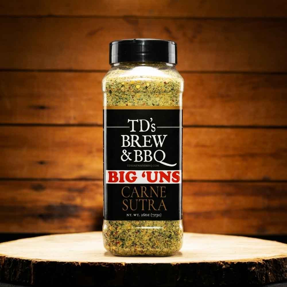 Spice jar labeled 'TD's Brew & BBQ Big 'Uns Carne Sutra' on a wooden surface with a wooden background.