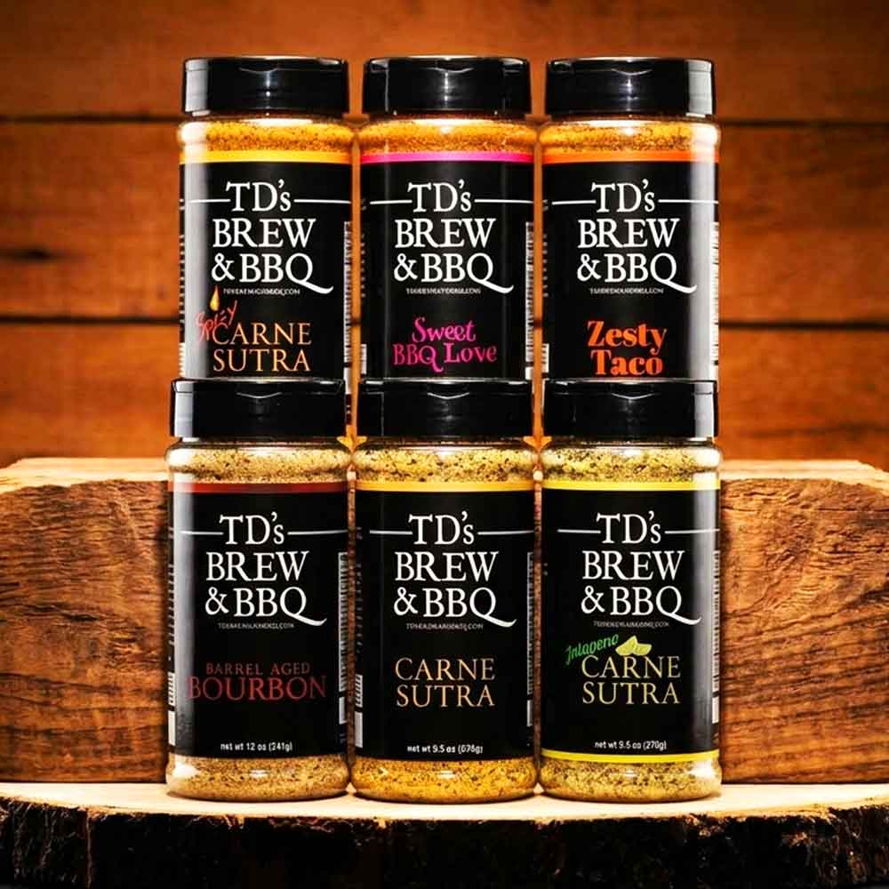 Collection of TD's Brew & BBQ spice jars on a wooden surface with a wooden background.