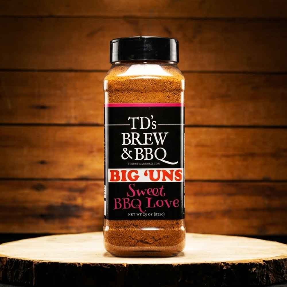Bottle of TD's Brew & BBQ Big 'Uns Sweet BBQ Love seasoning on a wooden surface with a wooden background.