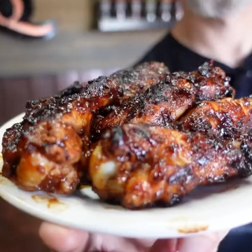 Plated barbecue chicken wings held by a person