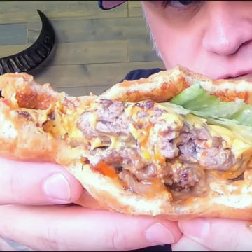 Person holding a half-eaten smash burger with visible ingredients