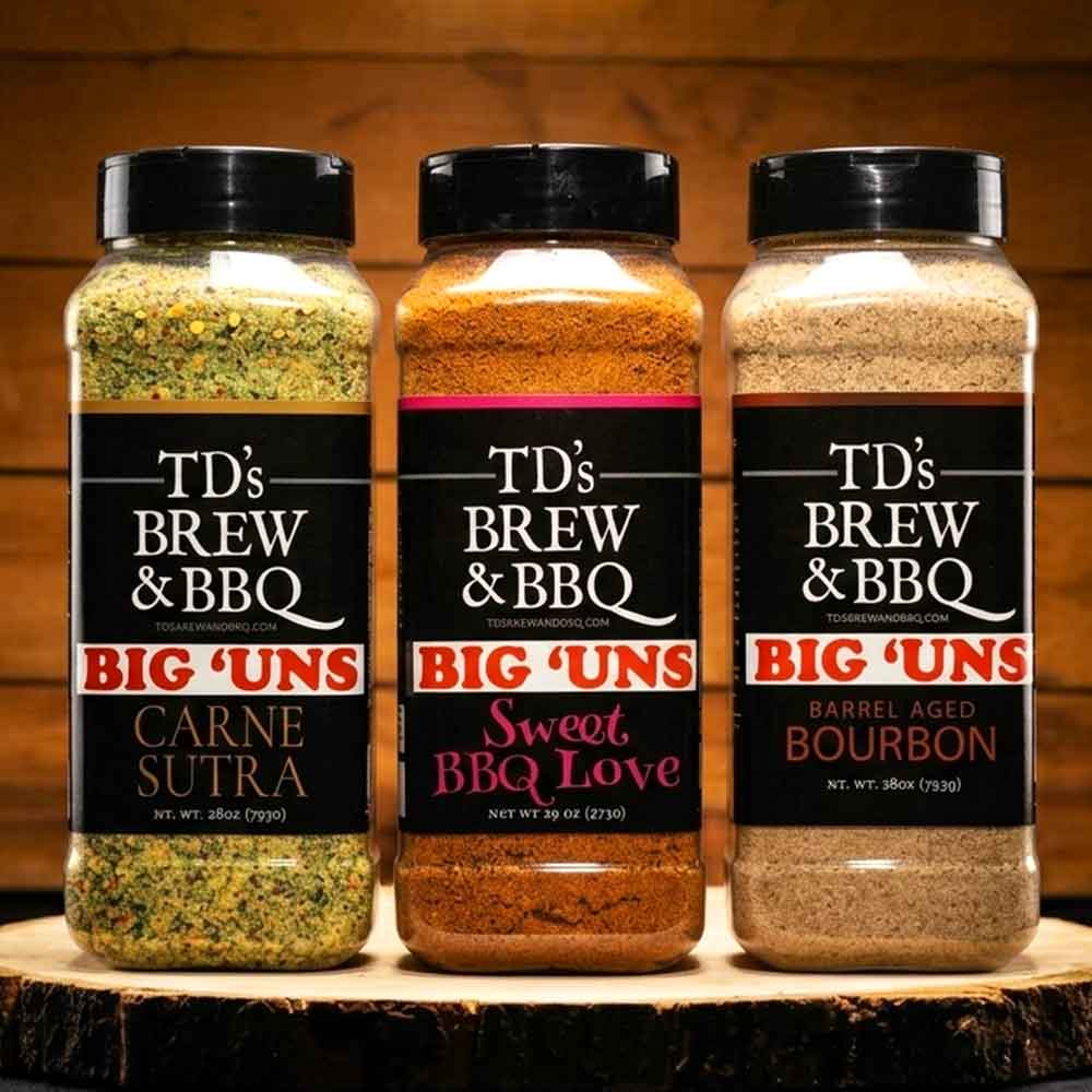 Three jars of TD's Brew & BBQ Big 'Uns seasoning on a wooden surface with a wooden background.