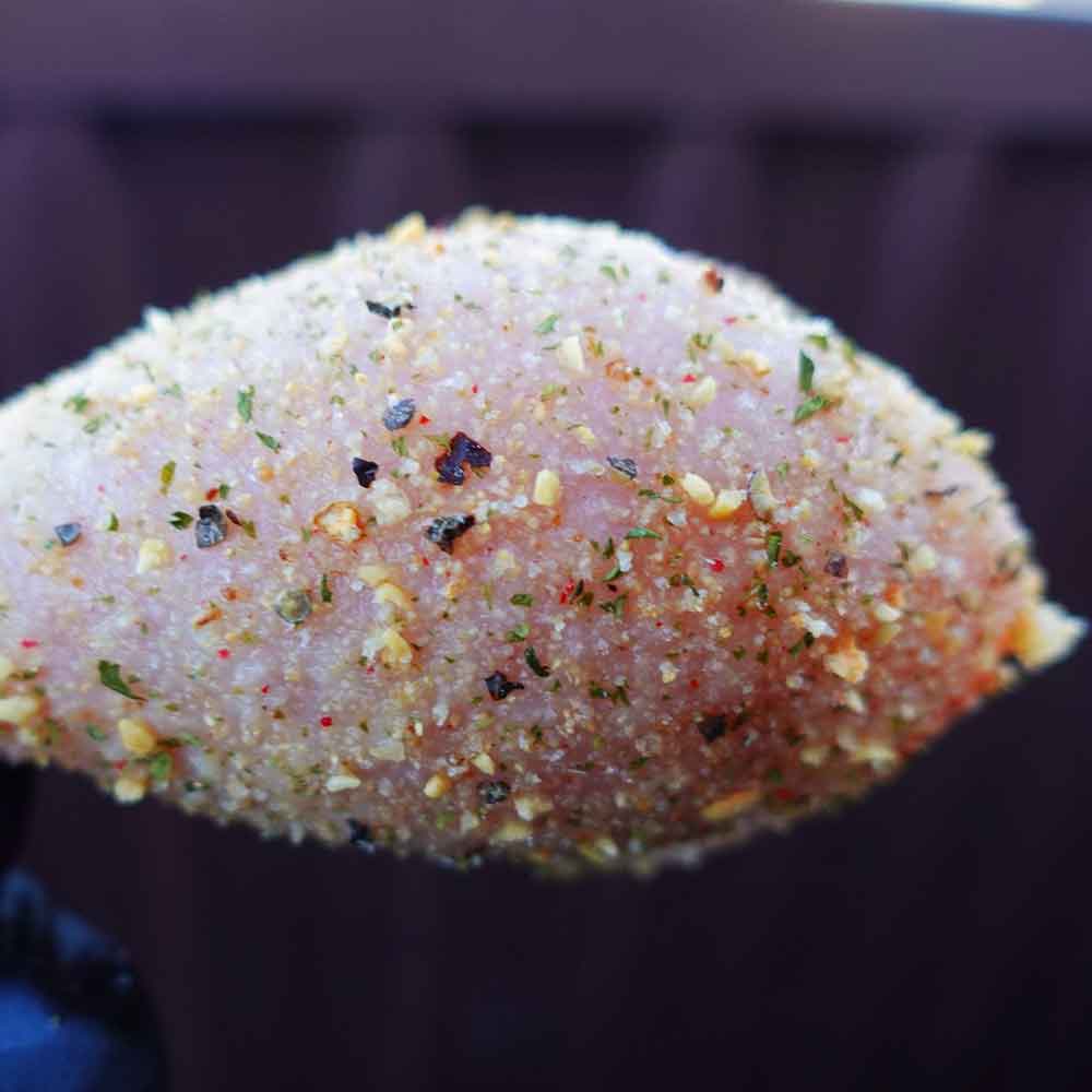 Raw chicken breast with seasoning on a dark background