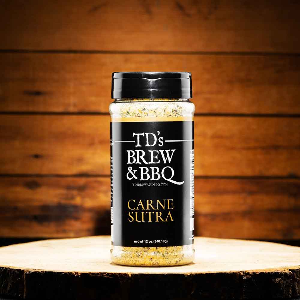 Bottle of TD's Brew & BBQ Carne Sutra seasoning on a wooden surface with a wooden background