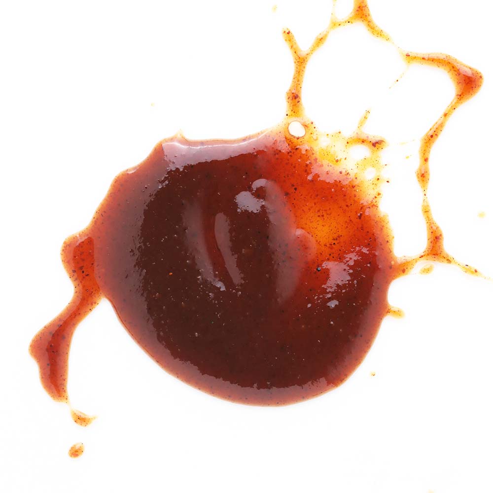 Bottle of TD's Brew & BBQ Cherry Chipotle sauce on a wooden surface with a wooden background