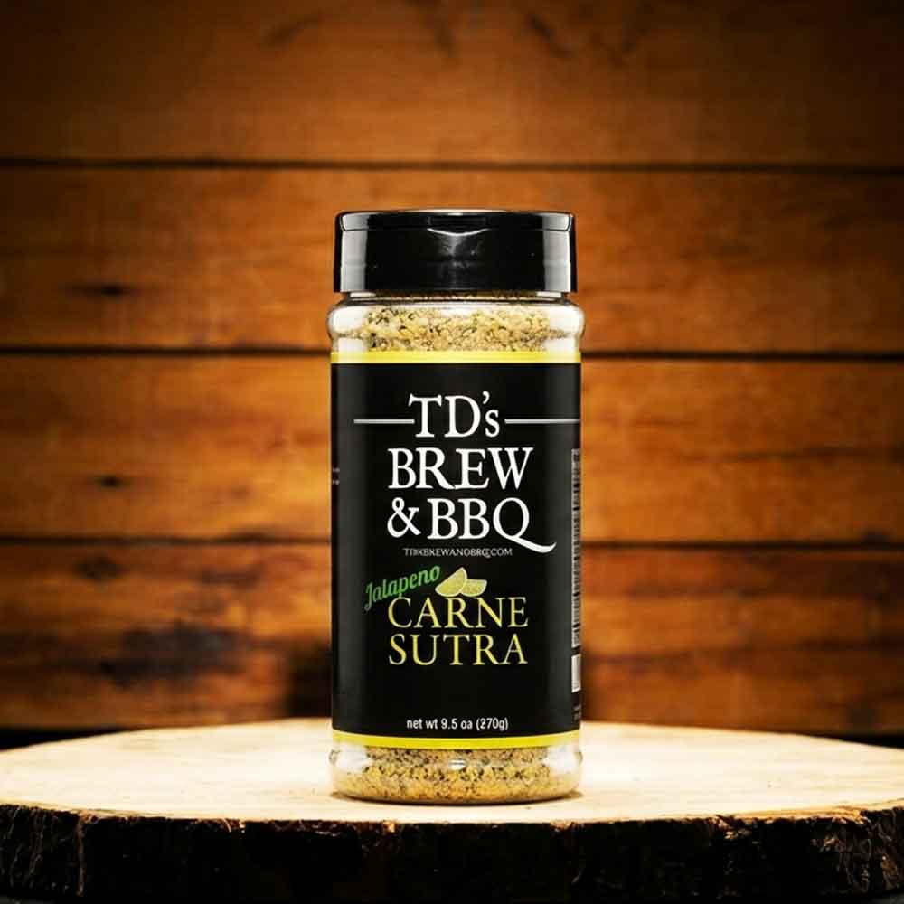 Jar of TD's Brew & BBQ Carne Sutra spice blend on a wooden surface with a wooden background
