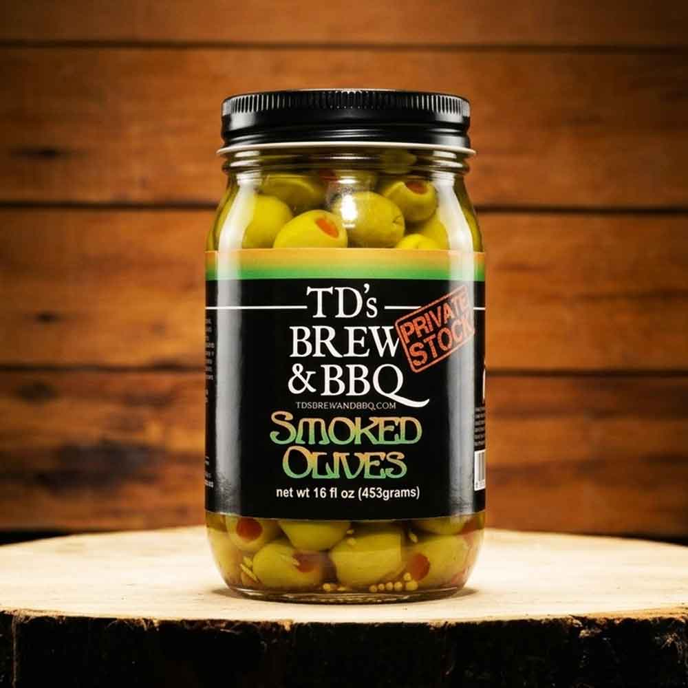 Jar of TD's Brew & BBQ Smoked Olives on a wooden surface with a wooden background