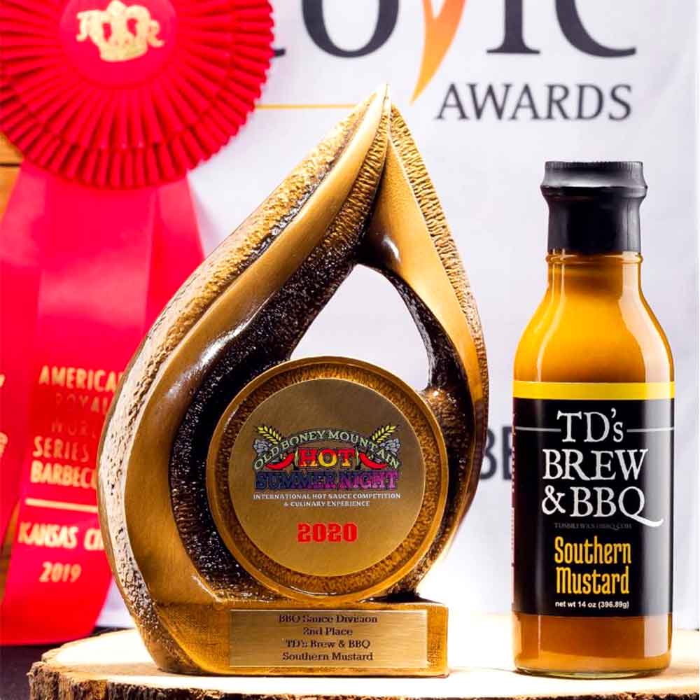 Gold trophy with 'Hot Sauce Heirloom' award and bottle of TD's Brew & BBQ Southern Mustard in front of a magazine cover.