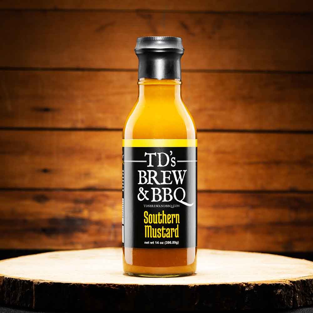 Bottle of TD's Brew & BBQ Southern Mustard on a wooden surface with a wooden background