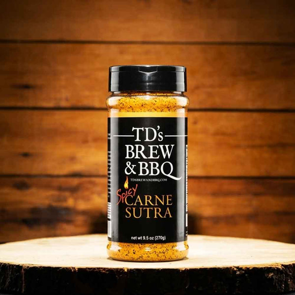 Bottle of TD's Brew & BBQ Spicy Carne Sutra seasoning on a wooden surface with a wooden background