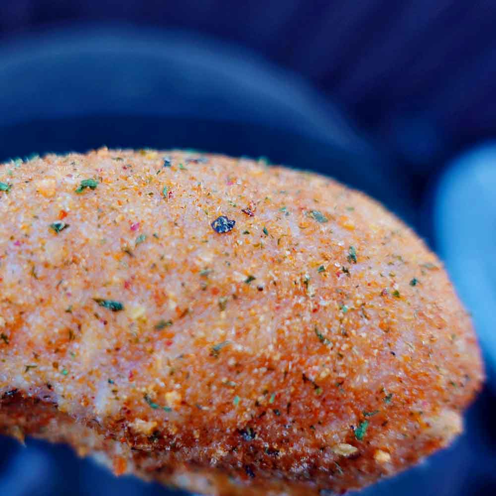Close-up of a chicken drumstick with seasoning on a blue background