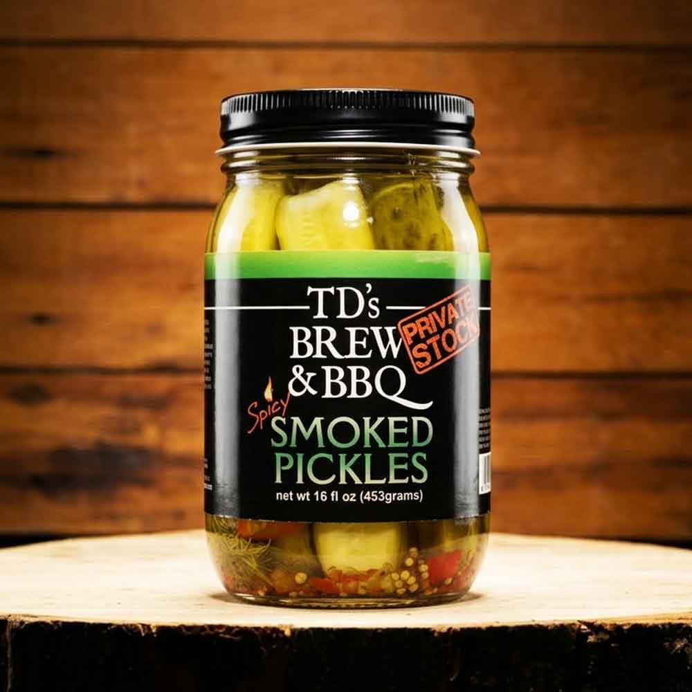 Jar of TD's Brew & BBQ Spicy Smoked Pickles on a wooden surface with a wooden background