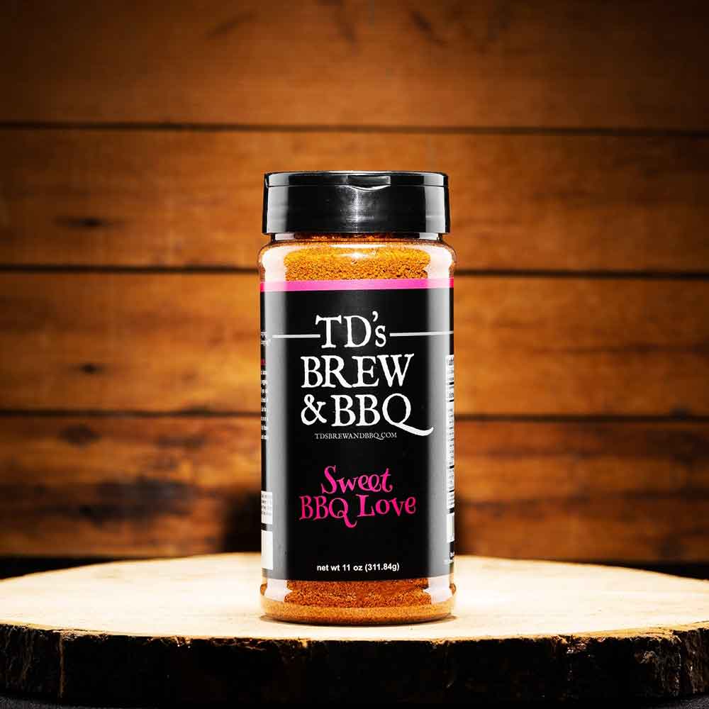 Jar of TD's Brew & BBQ Sweet BBQ Love seasoning on a wooden surface with a wooden background.