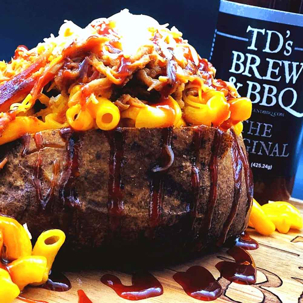 Baked potato with macaroni and cheese, pulled pork, and a bottle of TD's Brew & BBQ in the background.