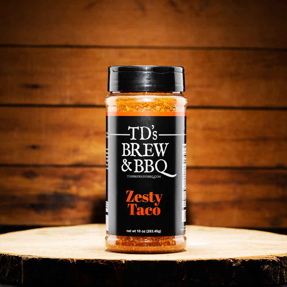 Jar of TD's Brew & BBQ Zesty Taco seasoning on a wooden surface with a wooden background
